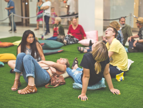 Group of people in a circle on the fake grass looking up the LED Constellation