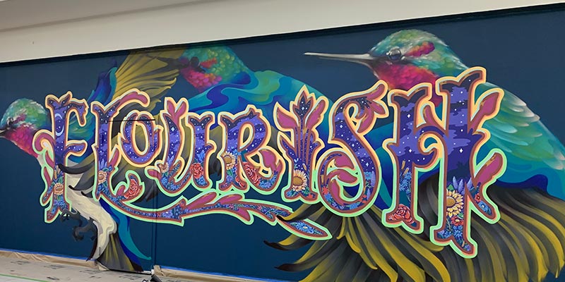 Mural with hummingbirds and the text, "Flourish."