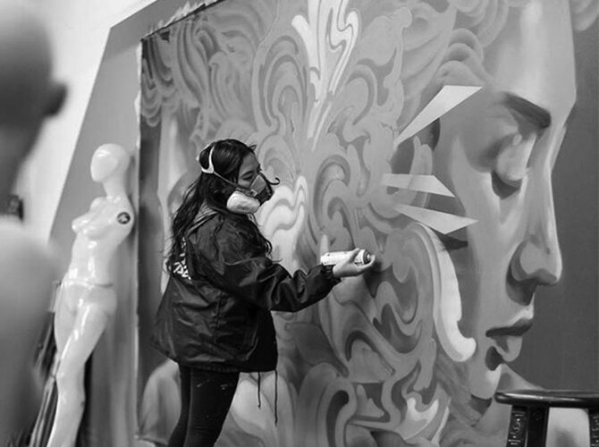 Artist, Franceksa Gamez painting a mural with spray paint.